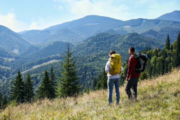 Fototapeta na wymiar Couple with backpacks enjoying mountain landscape on sunny day