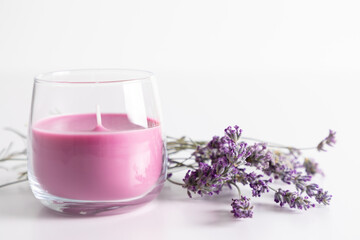Aroma candles with colorful wax in glass with sprig of dry lavender on white background.