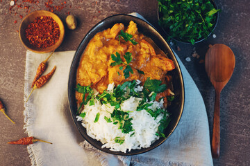 Traditional indian butter chicken in a bowl with basmati rice, spices and herbs