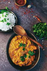 Traditional indian butter chicken in a bowl with basmati rice, spices and herbs