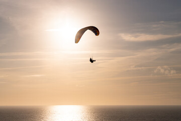Céu imenso com individuo a fazer parapente ao pôr-do-sol