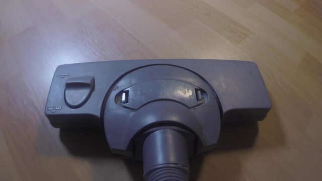 A vacuum cleaner moves across a laminate in a cheap apartment. Cleaning of dust in the house, cleanliness and order. Garbage collection.