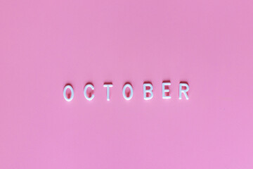 Flat lay top view of word October on pink background. October it's breast cancer awareness month