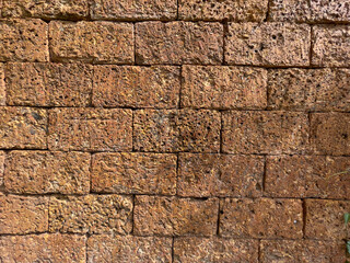 Laterite brick wall background and texture. Natural Laterite rock for outdoor and tropical garden or Bali garden wall decoration. Selective focus