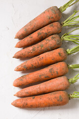 a bunch of fresh raw carrots with leaves on white table
