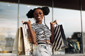excited african american woman holding shopping bags, shopping on black friday, low prices