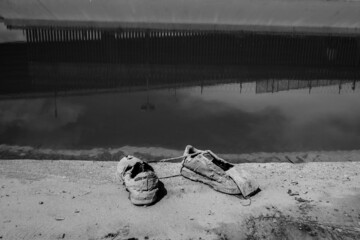 Abandoned migrant shoes on the banks of the Rio Bravo in Ciudad Juarez Chihuahua Mexico