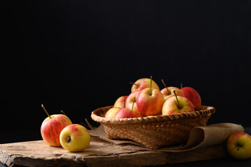 Fresh red apple fruit in a basket on wooden with black background, Still Life