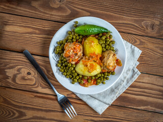 Light plate on a linen napkin with meatballs and vegetables, canned green peas