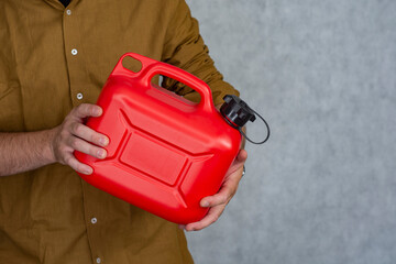 Man holds a red plastic gas canister in his hands.