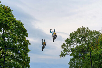 Motocross riders perform stunts in the air