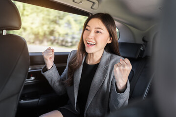 cheerful successed business woman sitting at the back seat of car