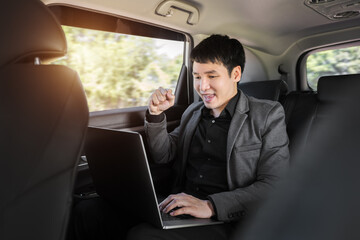 successful business man using laptop computer while sitting in the back seat of car
