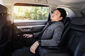 business man sleeping while sitting in the back seat of car