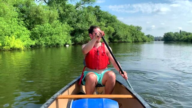 Athletic Man In Red Buoyancy Vest Paddles Canoe On River Wye In Sun