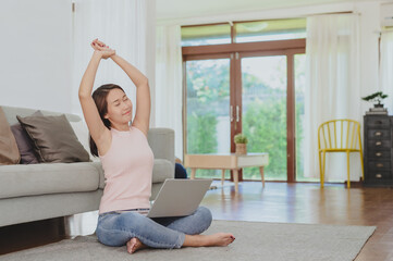 Fototapeta na wymiar Happy Asian woman stretching after using laptop working at home