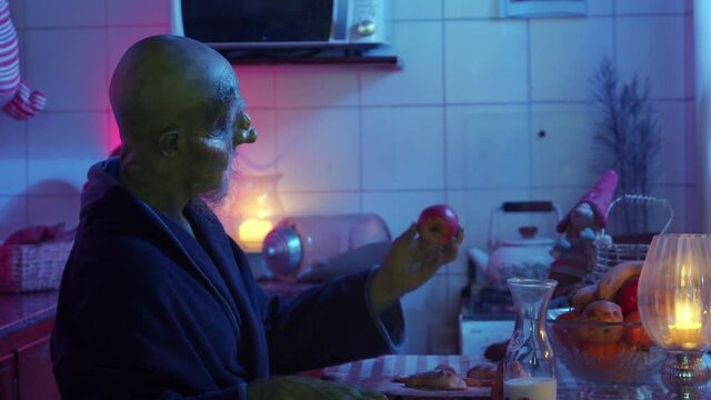 Green monster eating a banana at home on halloween night, closeup
