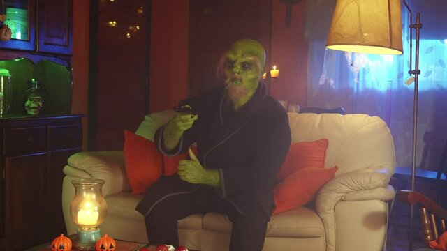 Green monster watching TV at home at night