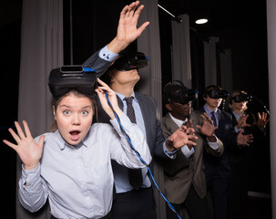 Portrait of happy excited girl wearing VR glasses spending tine with her colleagues in...