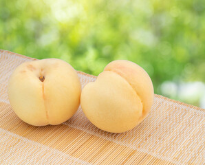 Fresh Yellow Peach over blurred greenery background, Yellow Peach Peach fruits on bamboo mat.