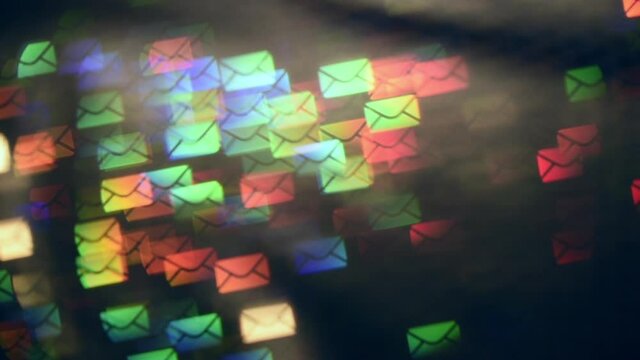 Multiple email envelopes moving against dark background. Envelop-shaped blur bokeh move in rays and shimmer with the colors of the rainbow. Global social media connection concept. Light leaks.