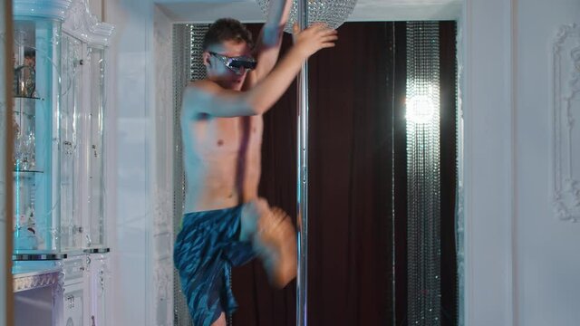 A young man shirtless expressive dancing at a pole in glasses with rhinestones