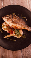 dorado fish on a plate with garnish and pesto sauce top view