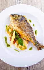 dorado fish on a plate with garnish and pesto sauce top view