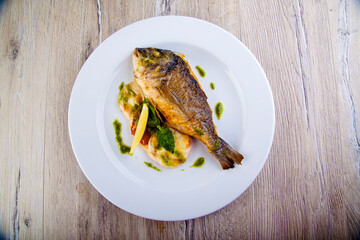 dorado fish on a plate with garnish and pesto sauce top view