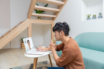 Asian man sitting on the floor and playing on the computer, feeling tired