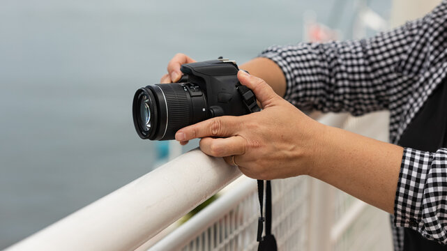 Female hands holding photo camera ready for taking photos outdoor.