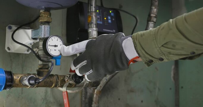 Plumber switching on artezic pump and checking barometer for pressure. Clean water supply.