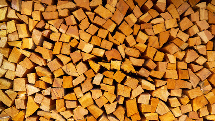 Firewood cut and stacked. Wall of wooden pieces. Warm colors with shades of brown. Wood stacked with precision. Wooden natural cut logs texture background