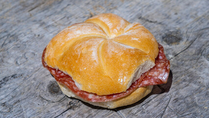 Crispy salami sandwich. Stuffed sandwich on wooden table