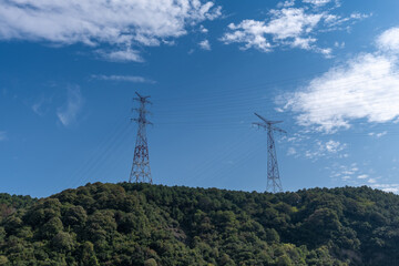 high voltage transmission towers in the forest on the hill