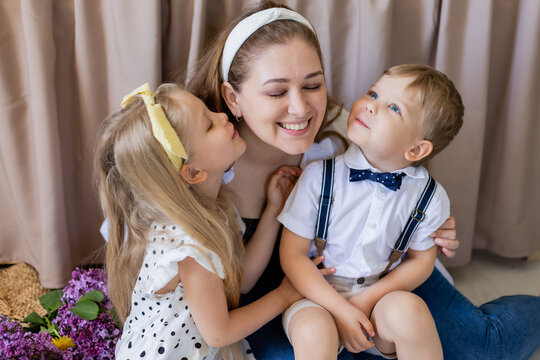 brother and sister kiss their mother. a smiling woman embraces two children. the concept of a happy family. Lifestyle. High quality photo