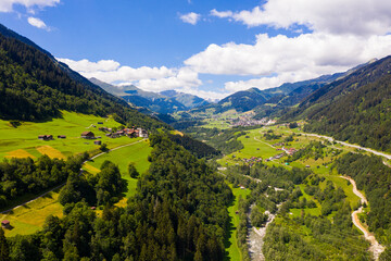 Fototapeta na wymiar Picturesque aerial view of houses of small Swiss village Cavardiras in mountain valley in sunny summer day