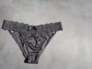 Dark blue sexy panties made of silk and guipure on a gray background. High quality photo