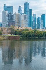 Fototapeta na wymiar City view of buildings of different storeys, reflected in the Moskva river, vertical Moscow photo