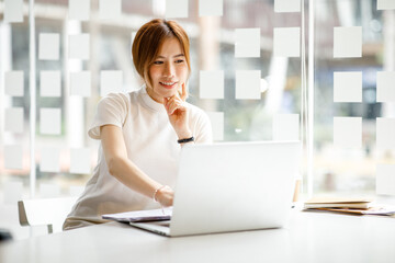 A young woman or businesswoman working on laptop computer in modern office. doing finances, accounting analysis, report data pointing graph Freelance education and technology concept.