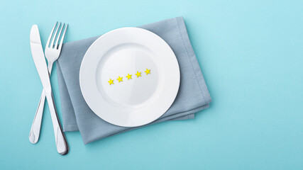 Gold stars on white plate with fork and knife on blue background