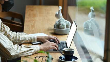 Man freelancer sitting at comfortable workplace and working with laptop computer.