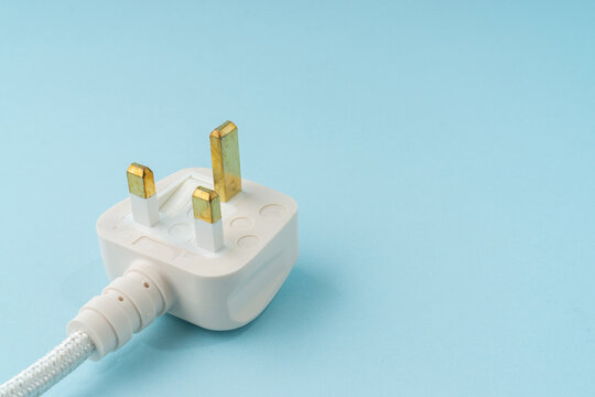 Three pin plug on light blue background with a copy space.