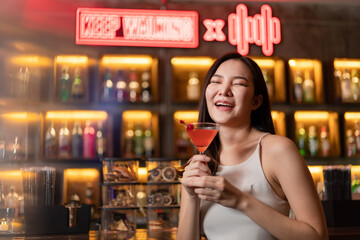 Nightlife concept a pretty girl with long hair wearing white and jeans holding a pink drink appreciating the musics alone in the bar