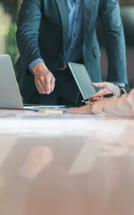 Cropped shot of business people hand pointing on paperwork on table while discussing together at office.