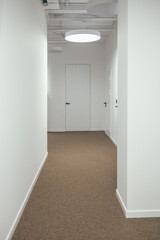 A white corridor, a white door. Beautiful stylish interior.