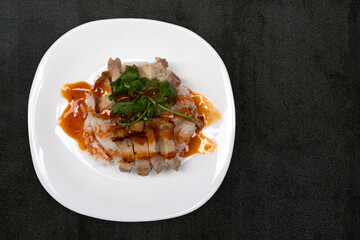 Top view of Rice crispy pork on white plate. Background of a dark tone color tiled table surface.