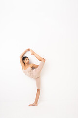 Girl doing stretching in the studio on a white background. A beautiful gymnast with a flexible body and athletic uniform.