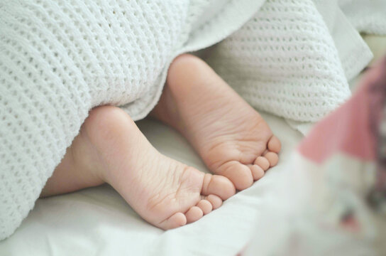 Gentle image of children's legs looking out from under the blanket. The concept of a happy childhood