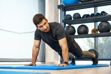 Fototapeta na wymiar Young athletic man doing push-ups in a gym, close up